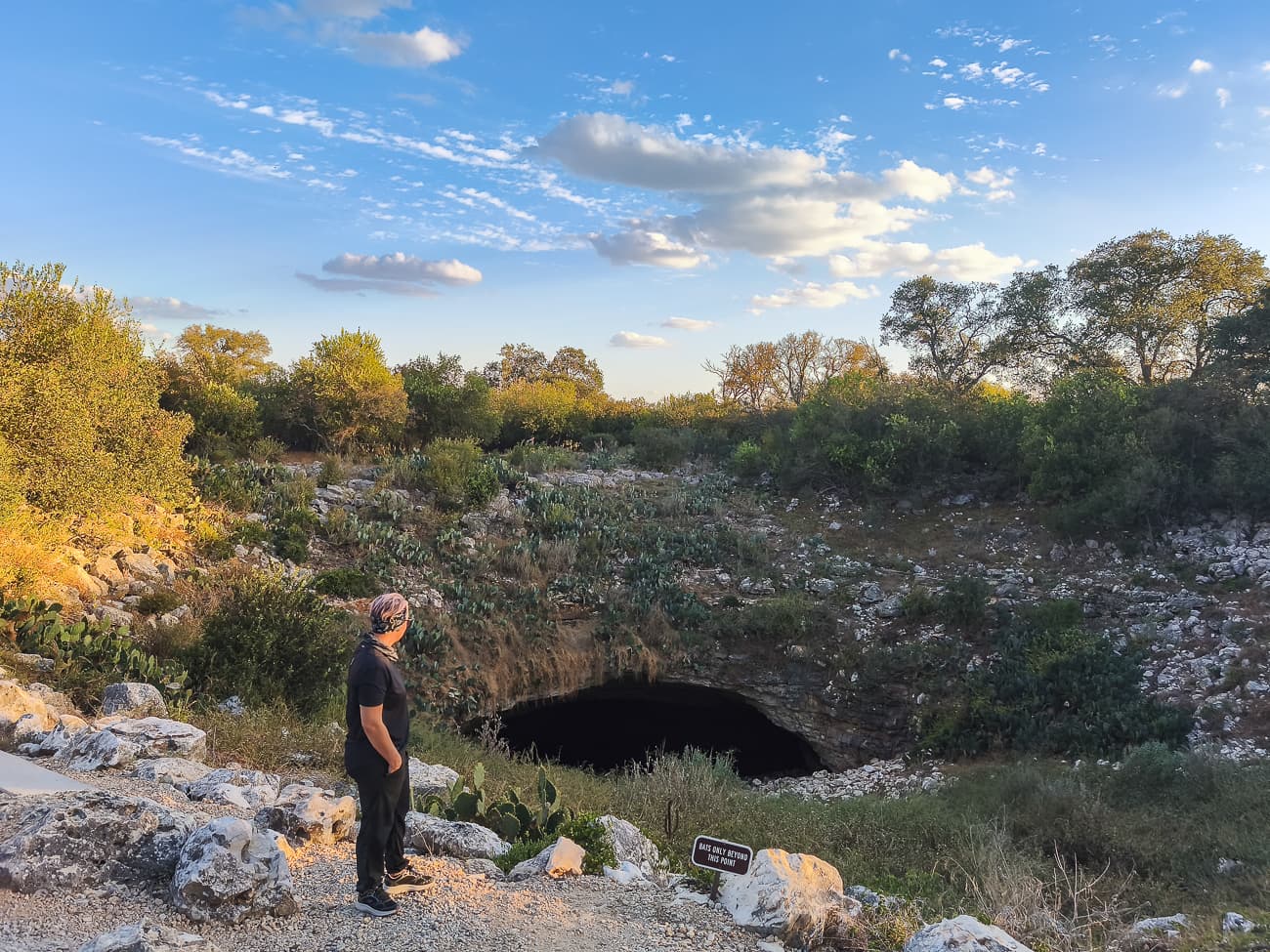 Entrada de la Cueva Bracken al atardecer, con profesional observando el lugar