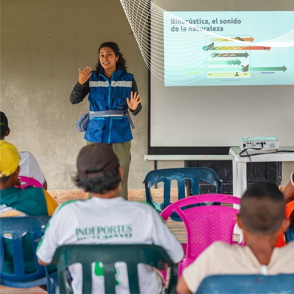 Investigadora de Cuántico presentando conceptos de bioacústica a comunidad indígena durante taller de participación en Orito, Putumayo, Colombia.